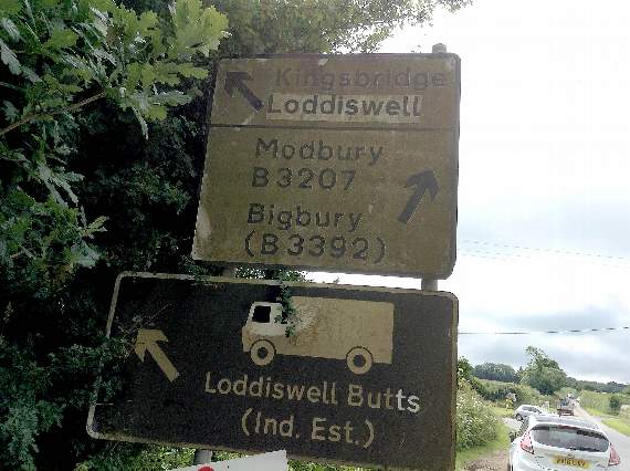 Dirty road sign at California Cross barely readable