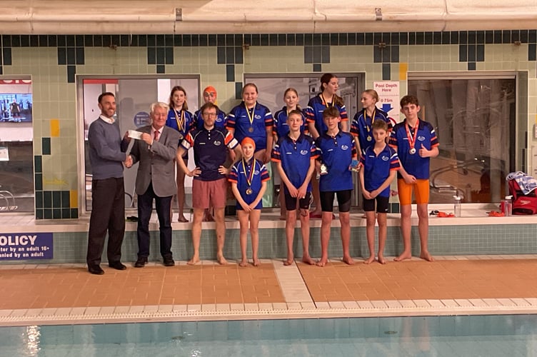 Jeremy Wilks, charity representative, from Kingsbridge Freemasons presenting the cheque to Dan, with the head coach of KKSC Conor Morgan flanked by some members of the swimming club.